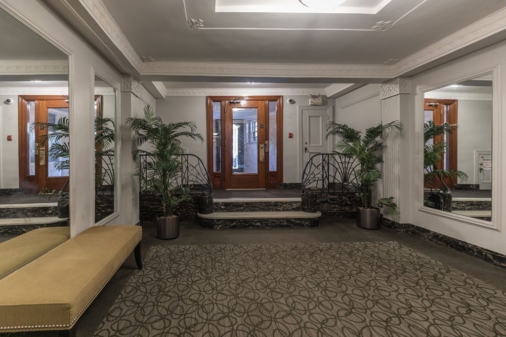 Building lobby with mirrored walls, ornate molding, marble steps, and patterned carpet.