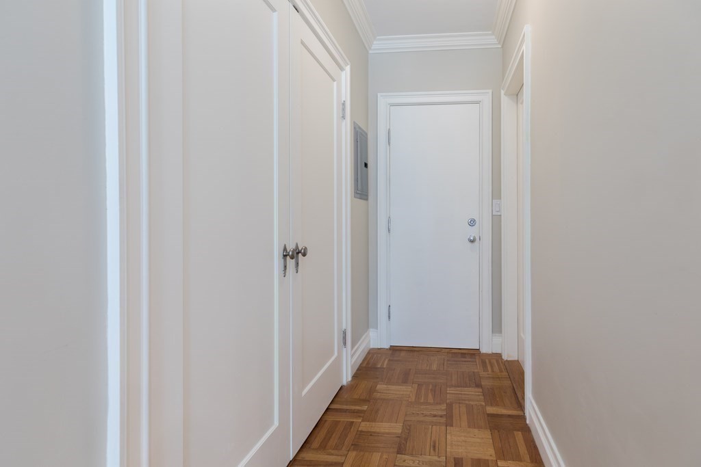 Empty hallway with white paneled doors and a patterned parquet floor.