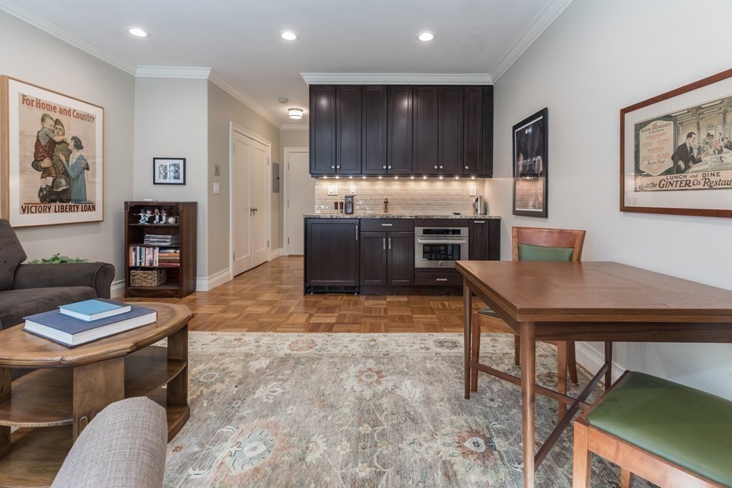 Open-plan living and dining area with dark kitchen cabinets and parquet flooring.