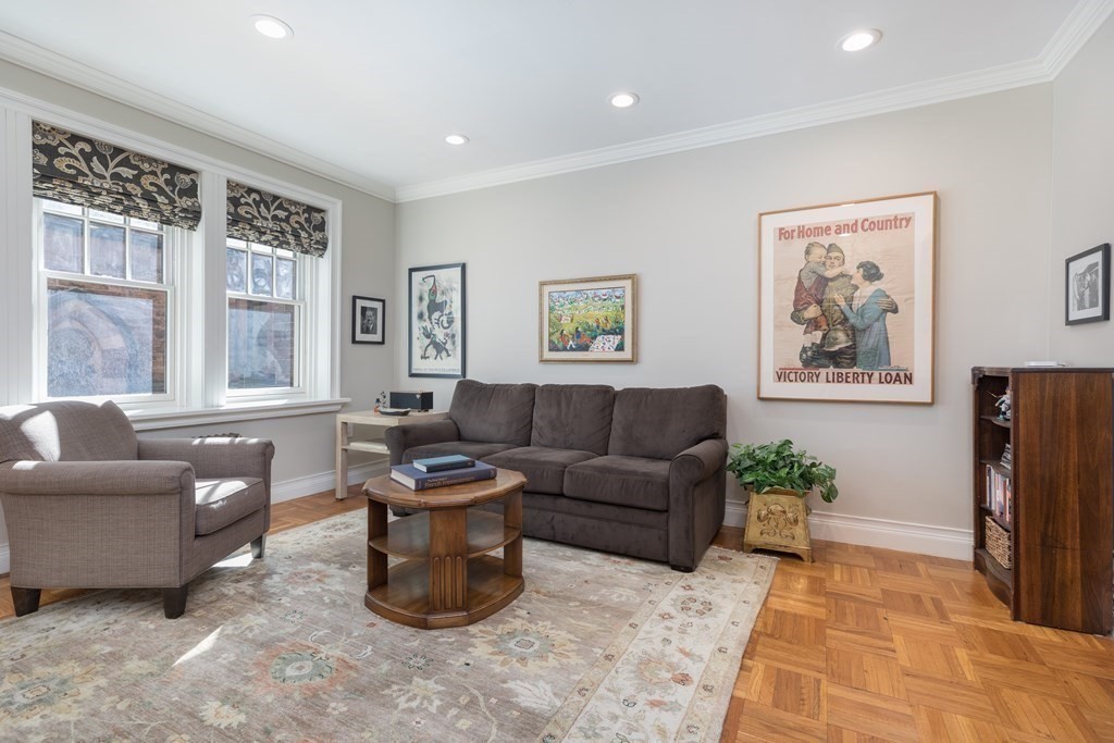 Living room with gray seating, tall windows, a patterned rug, and parquet floors.