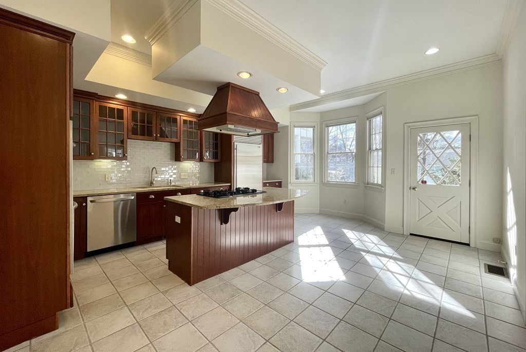 Kitchen with cherry cabinets, granite island and cooktop, tiled floors, and sunny bay windows.