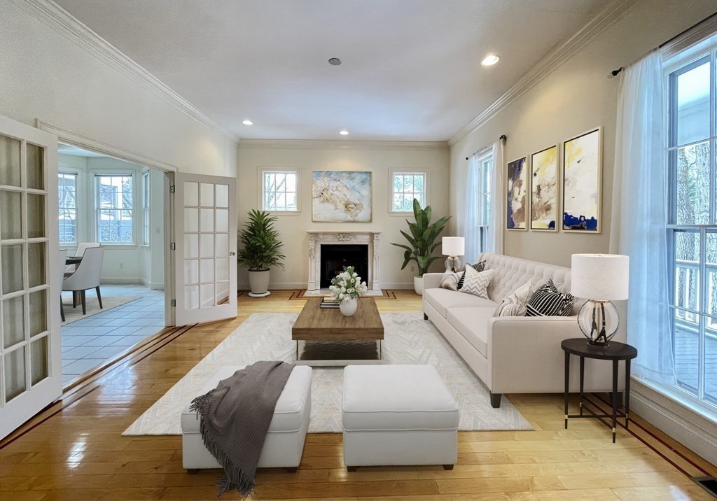 Staged living room with a fireplace, white sofa, hardwood floors, and large windows.