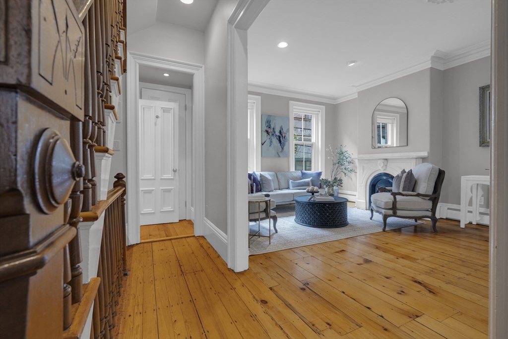 Living room with honey-toned wood floors, a gray sofa, and a white fireplace.