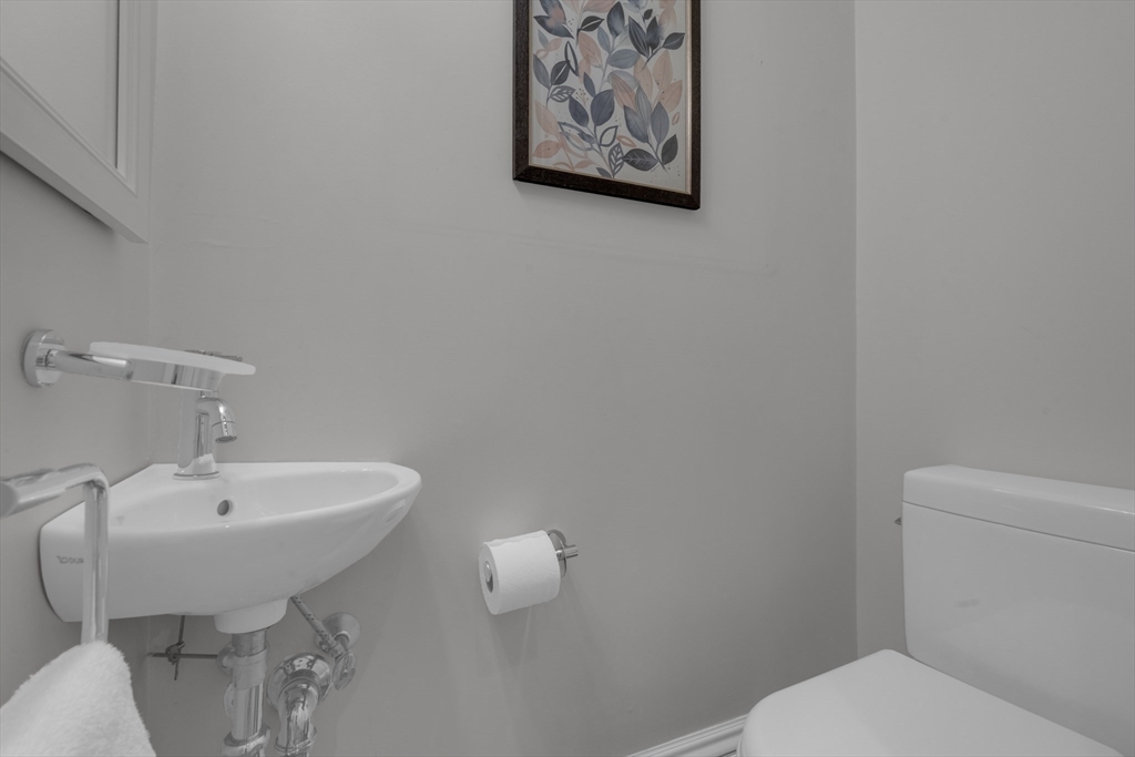 Bathroom with a wall-mounted faucet, white sink and toilet, and framed botanical artwork.