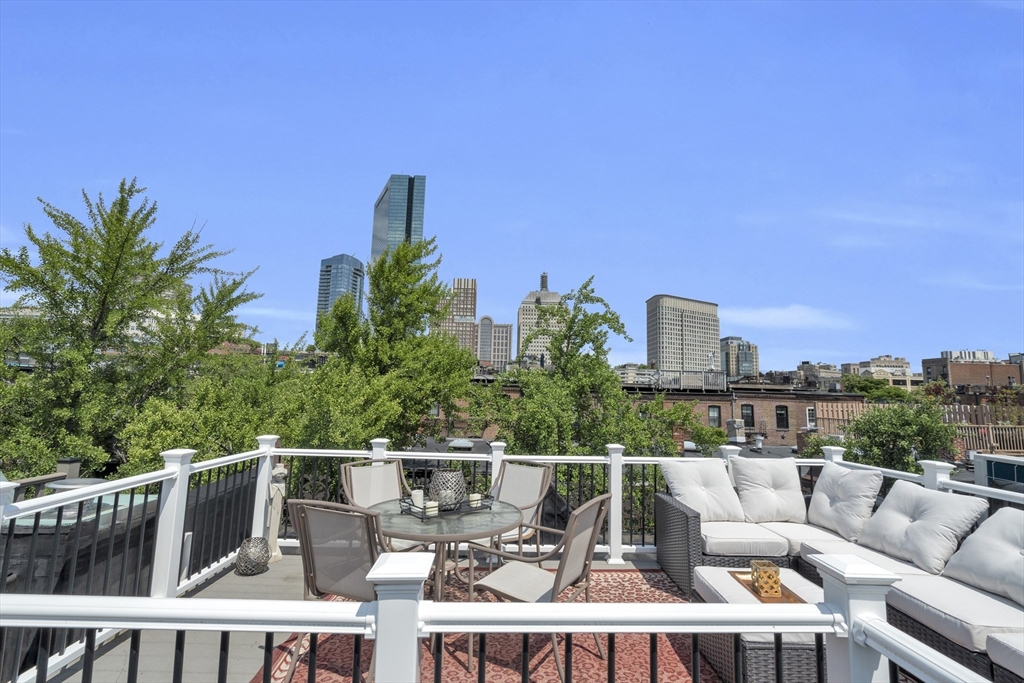 Furnished rooftop deck with outdoor dining and lounge seating overlooking the Boston skyline.