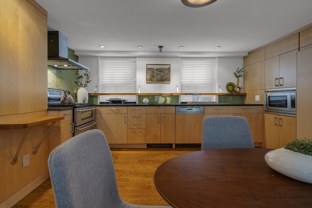 Kitchen with wood cabinetry, stainless steel appliances, and a round dining table.