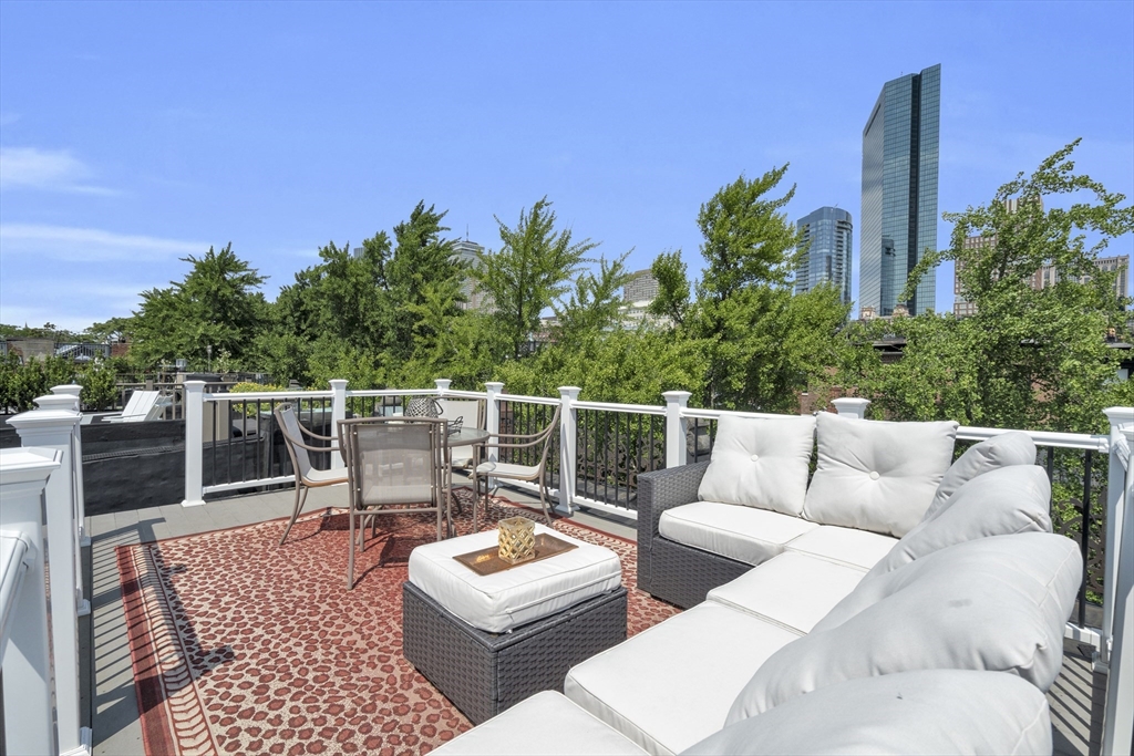 Furnished rooftop terrace with white-cushioned seating and Boston skyline views.