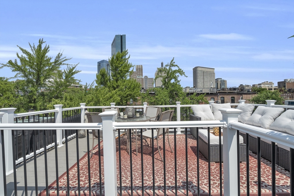 Rooftop deck with cushioned seating, a patterned rug, and Boston skyline views.