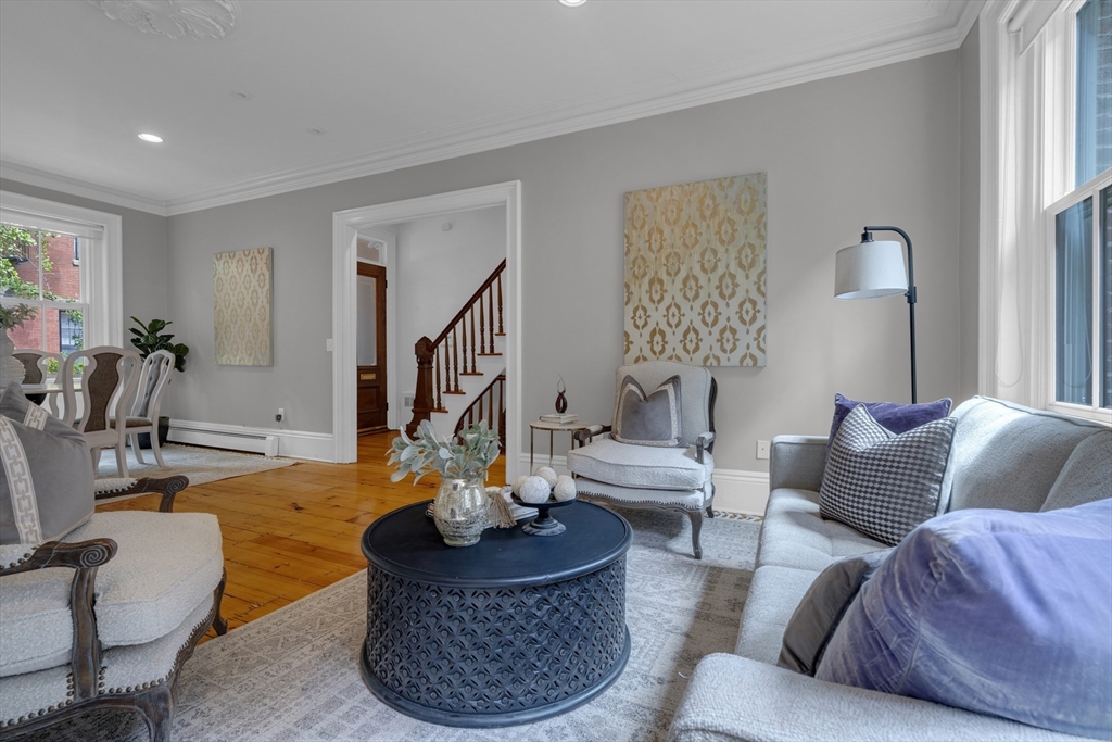 Staged living room with gray seating, a dark round coffee table, and honey-toned wood floors.