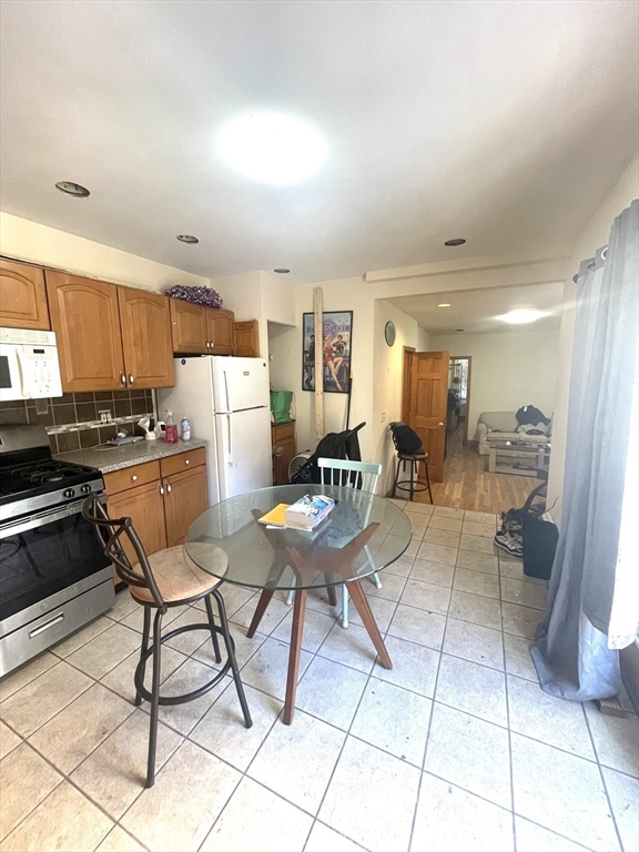 Kitchen with wood cabinets and stainless steel appliances, opening to a dining and living area.