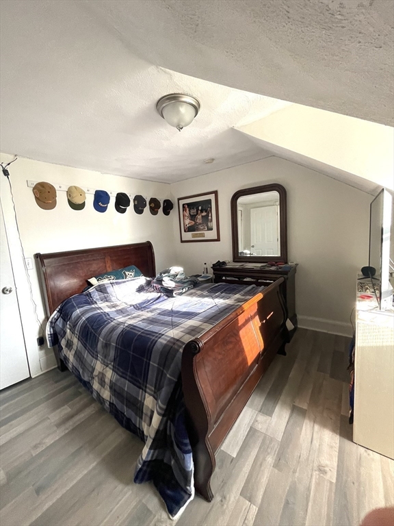 Bedroom with a dark wood sleigh bed, blue plaid bedding, and hats displayed along the wall.