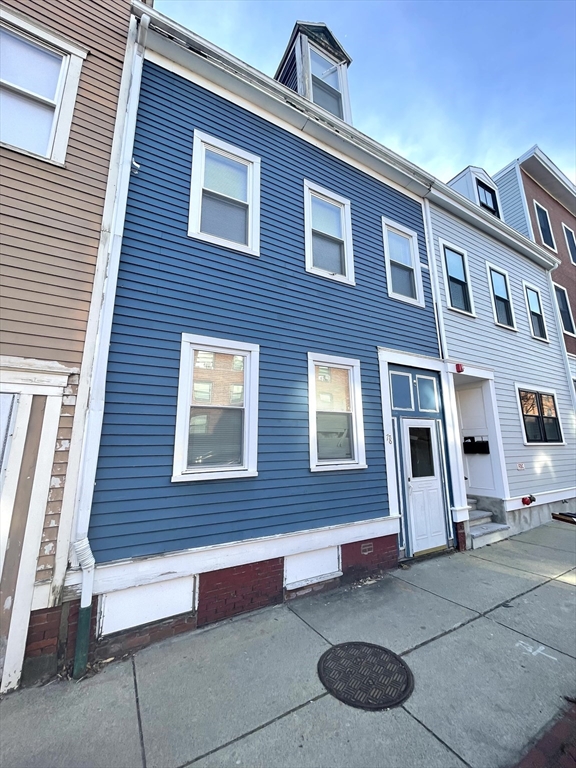 Blue-sided Boston home with white trim and a dark front door on a row of attached buildings.