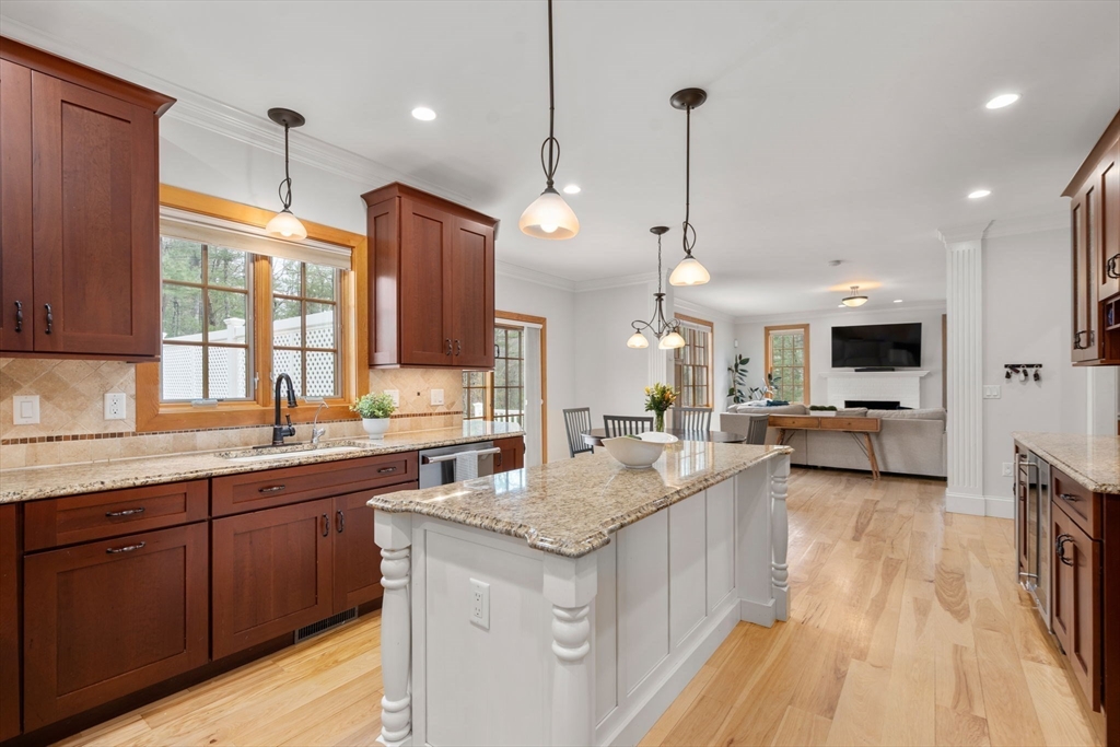 Kitchen with a large granite-topped island, dark wood cabinets, and an open living room beyond.
