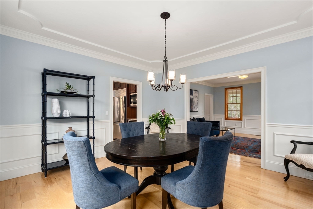 Dining room with a dark oval table, blue chairs, chandelier, and open doorways to the living room and kitchen.