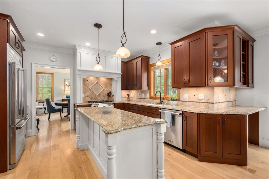 Kitchen with cherry cabinets, granite island, stainless steel appliances, and a tiled backsplash.
