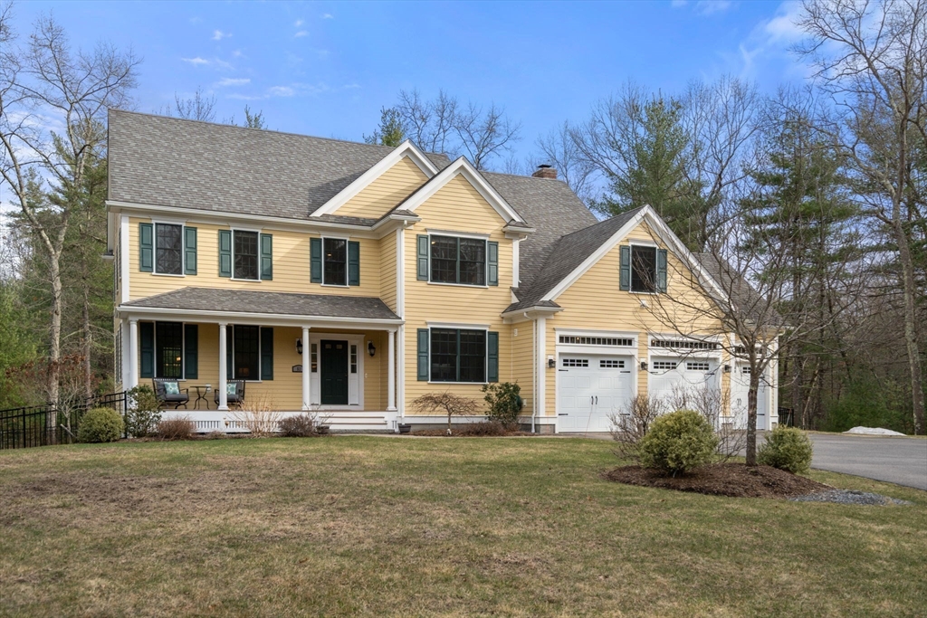 Yellow two-story house with green shutters, a covered porch, and an attached two-car garage.