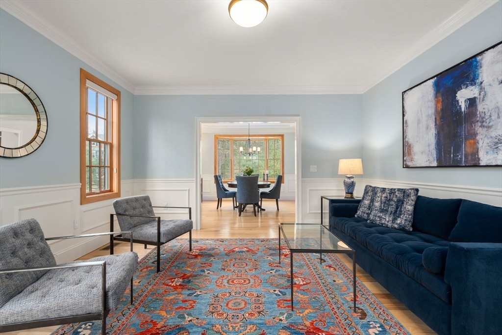 Living room with a navy sofa, patterned rug, and doorway to a bright dining room.