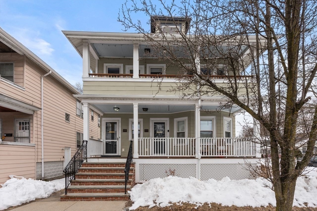 Front exterior of a two-story home with covered porches, brick steps, and a snow-covered yard.
