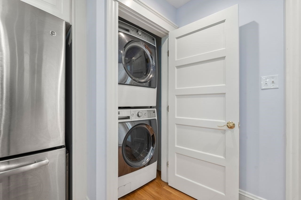 Stacked front-loading washer and dryer in a closet beside a stainless steel refrigerator.