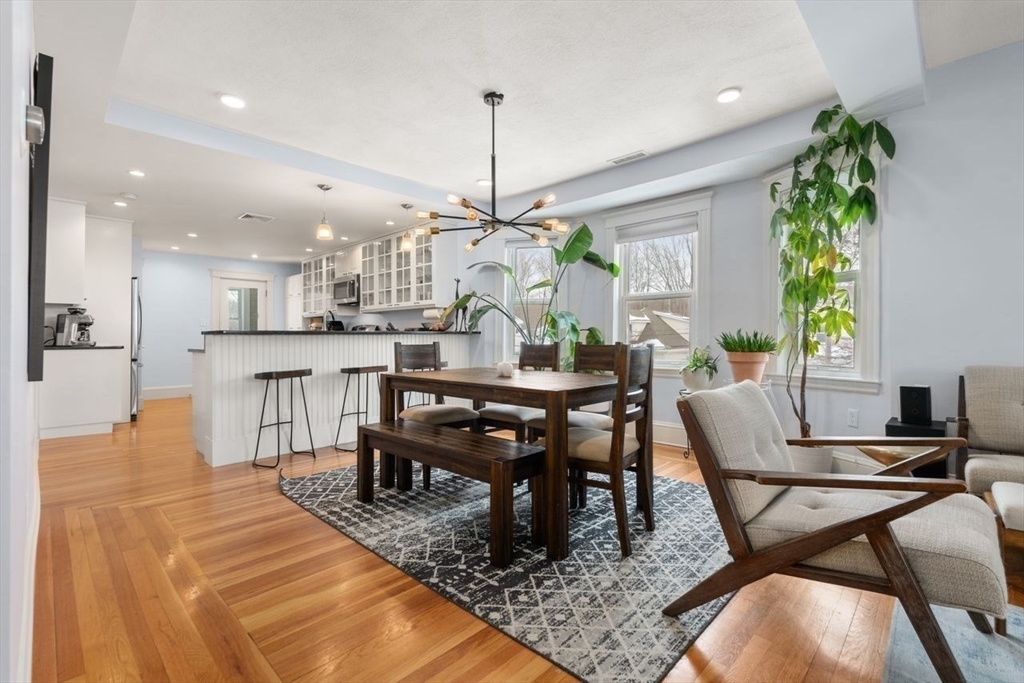 Open-plan kitchen and dining area with a dark wood table, patterned rug, and hardwood floors.