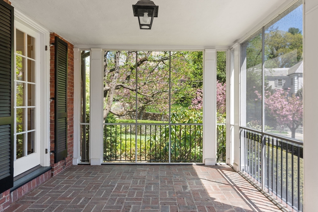 Enclosed porch with a brick floor and broad windows overlooking a spring garden.