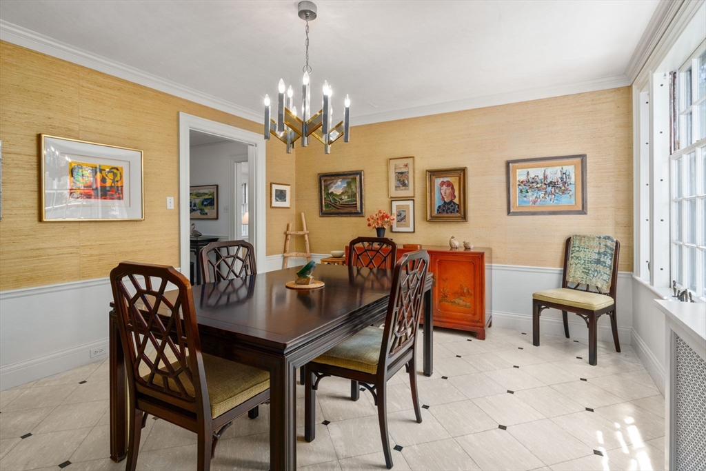 Furnished dining room with a dark wood table, cream tile floors, and framed artwork.