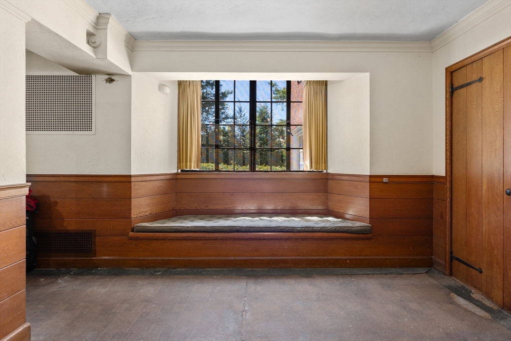 Empty room with a built-in wood window seat, paneled walls, and a large grid window.
