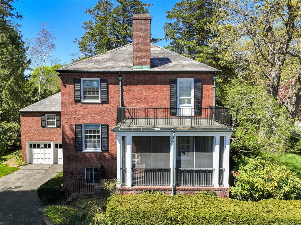 Red-brick house with an upper balcony, screened porch, and attached garage