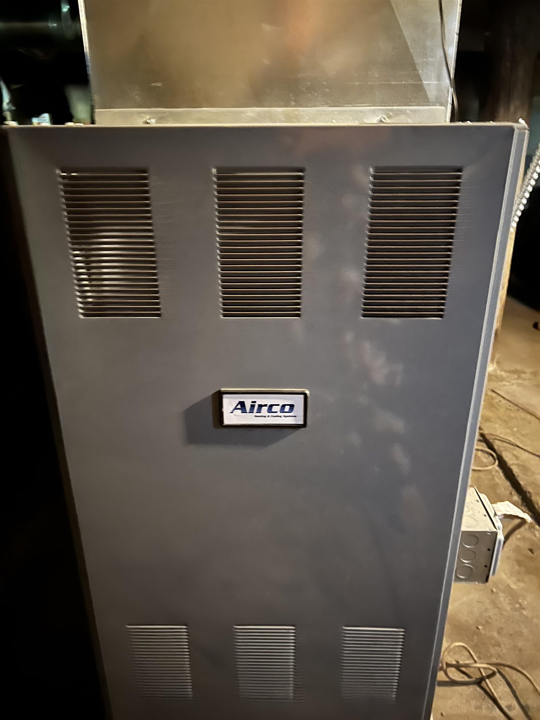 Gray Airco furnace with vented panels in a basement utility area.
