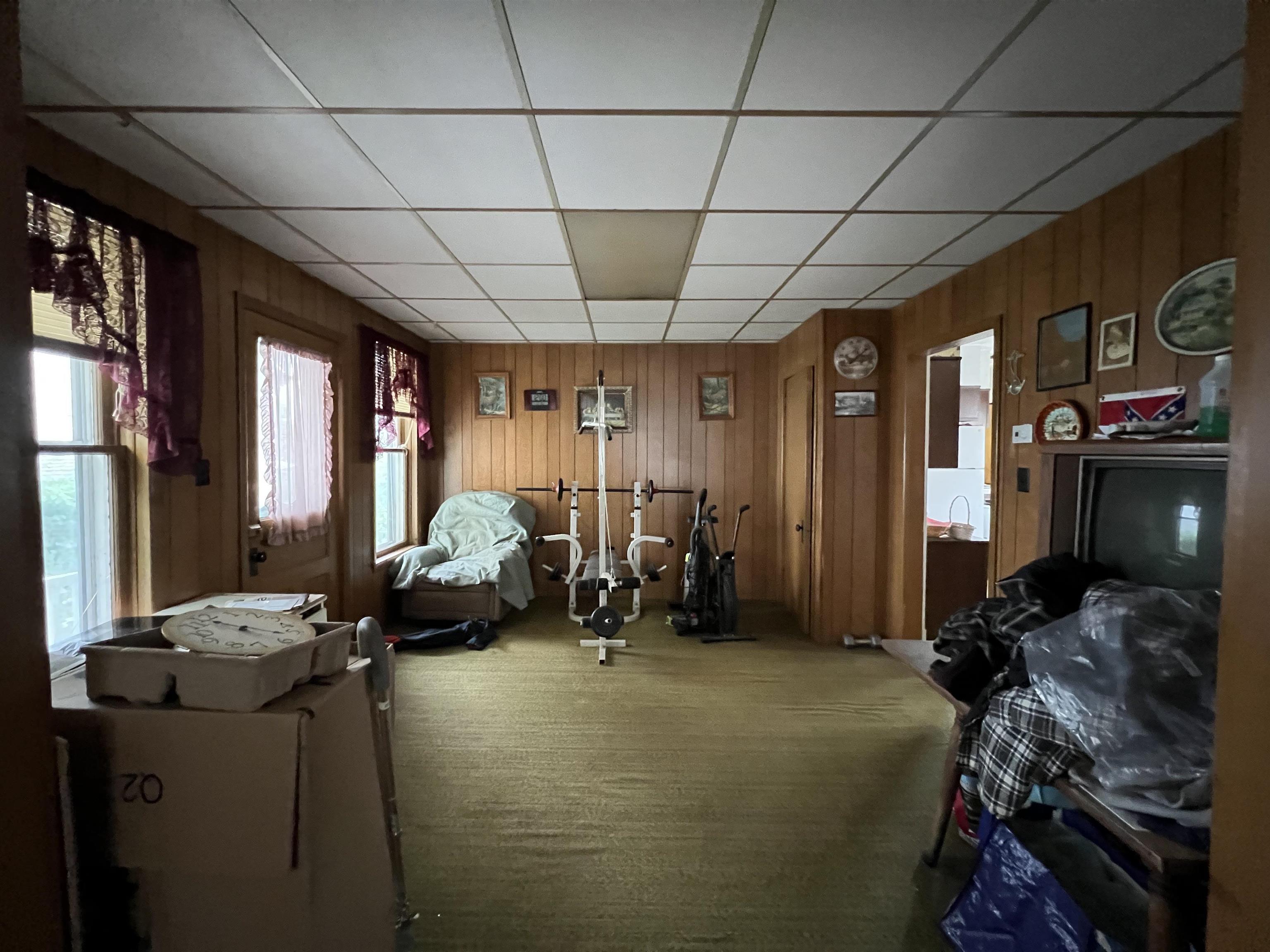 Wood-paneled room with exercise equipment, a television, and stored belongings.