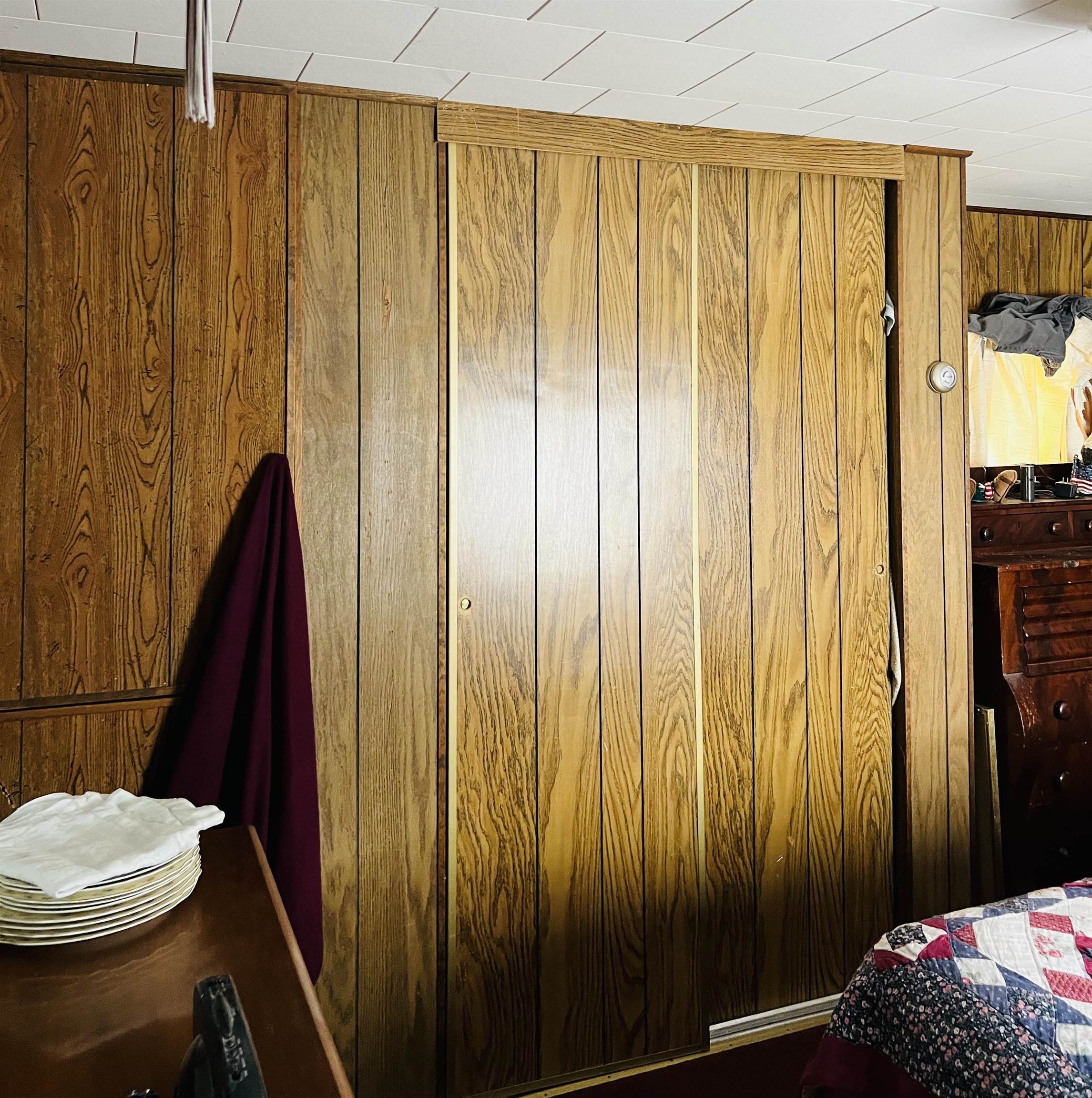 Bedroom with large wood-paneled sliding closet doors and a patterned quilt on the bed.
