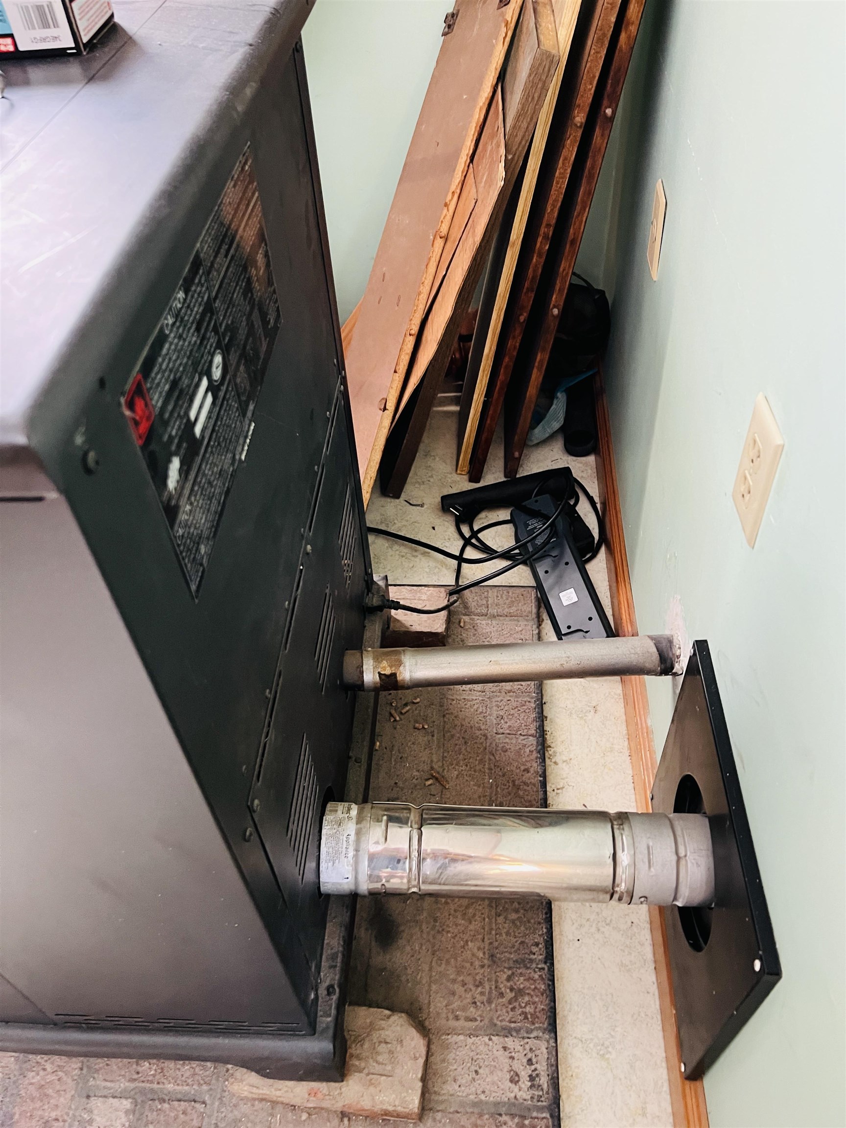 Heating appliance and vent pipes in a cramped utility area with boards and cables nearby.