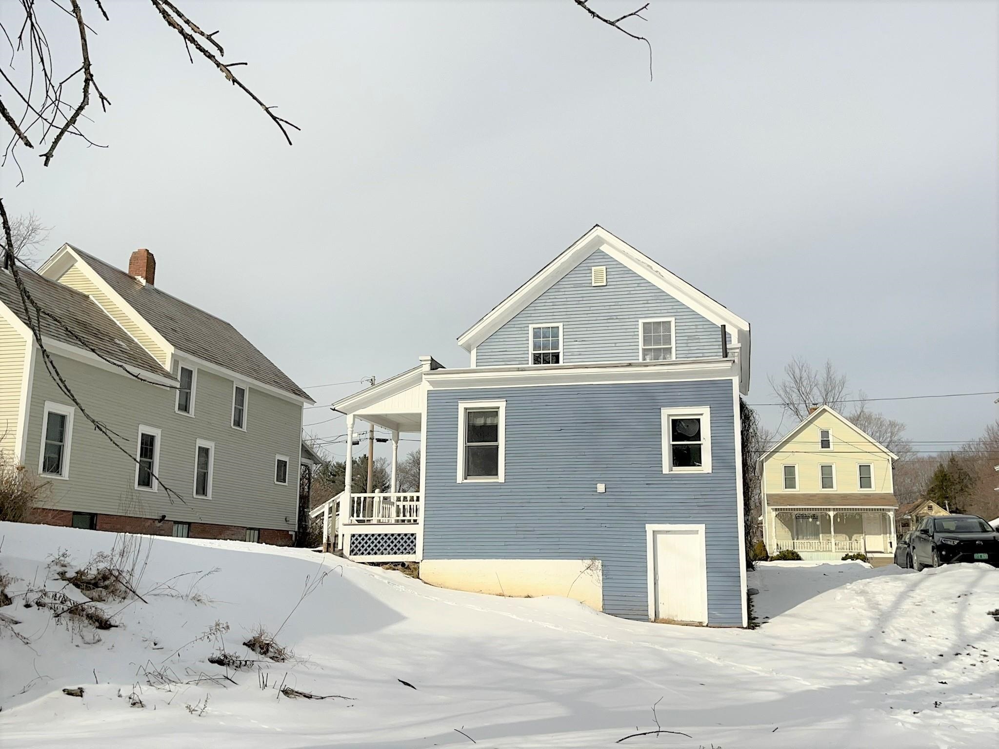 Blue two-story house with white trim and a covered porch, surrounded by snow.