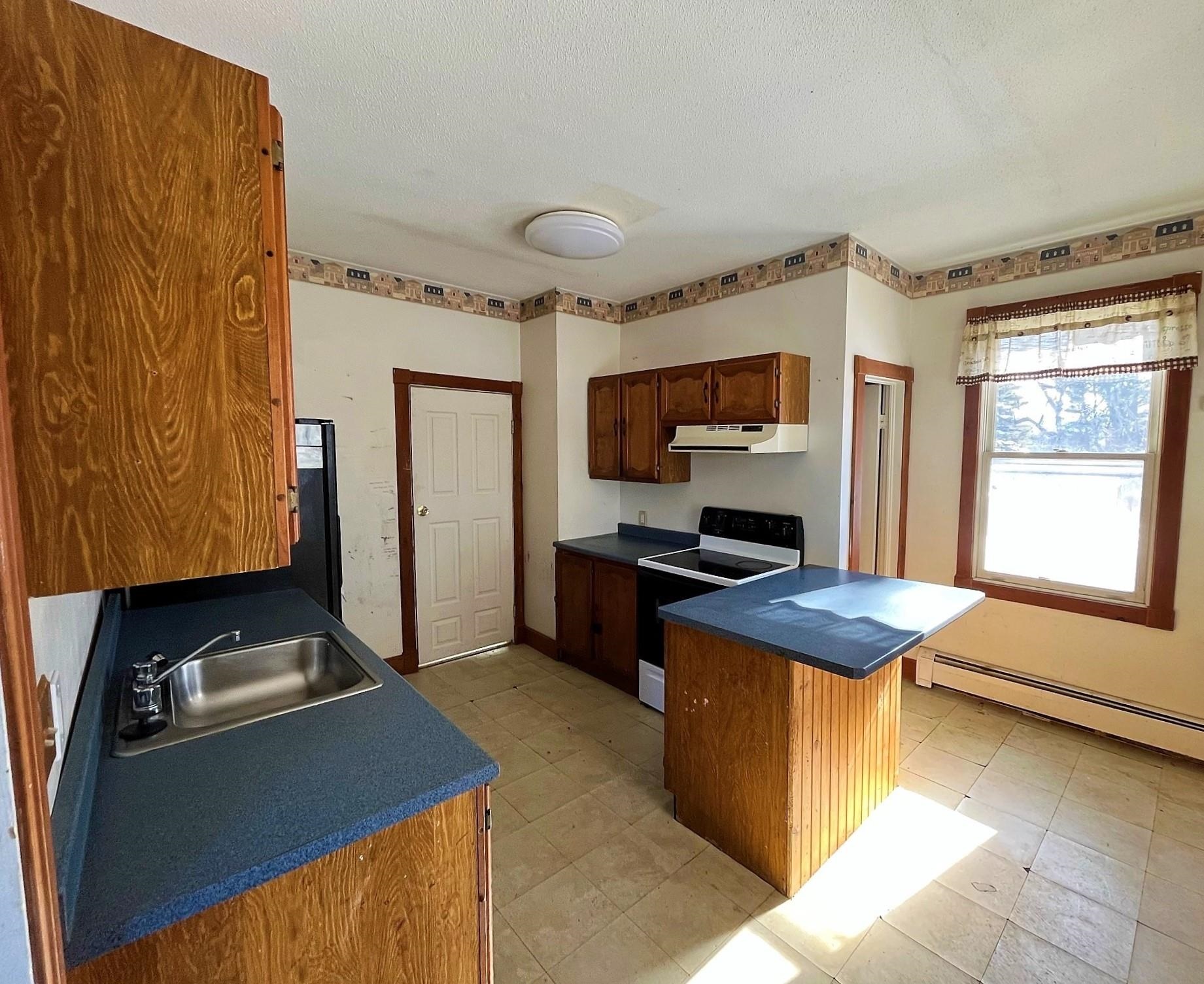 Kitchen with wood cabinets, blue countertops, a central island, and a large window.