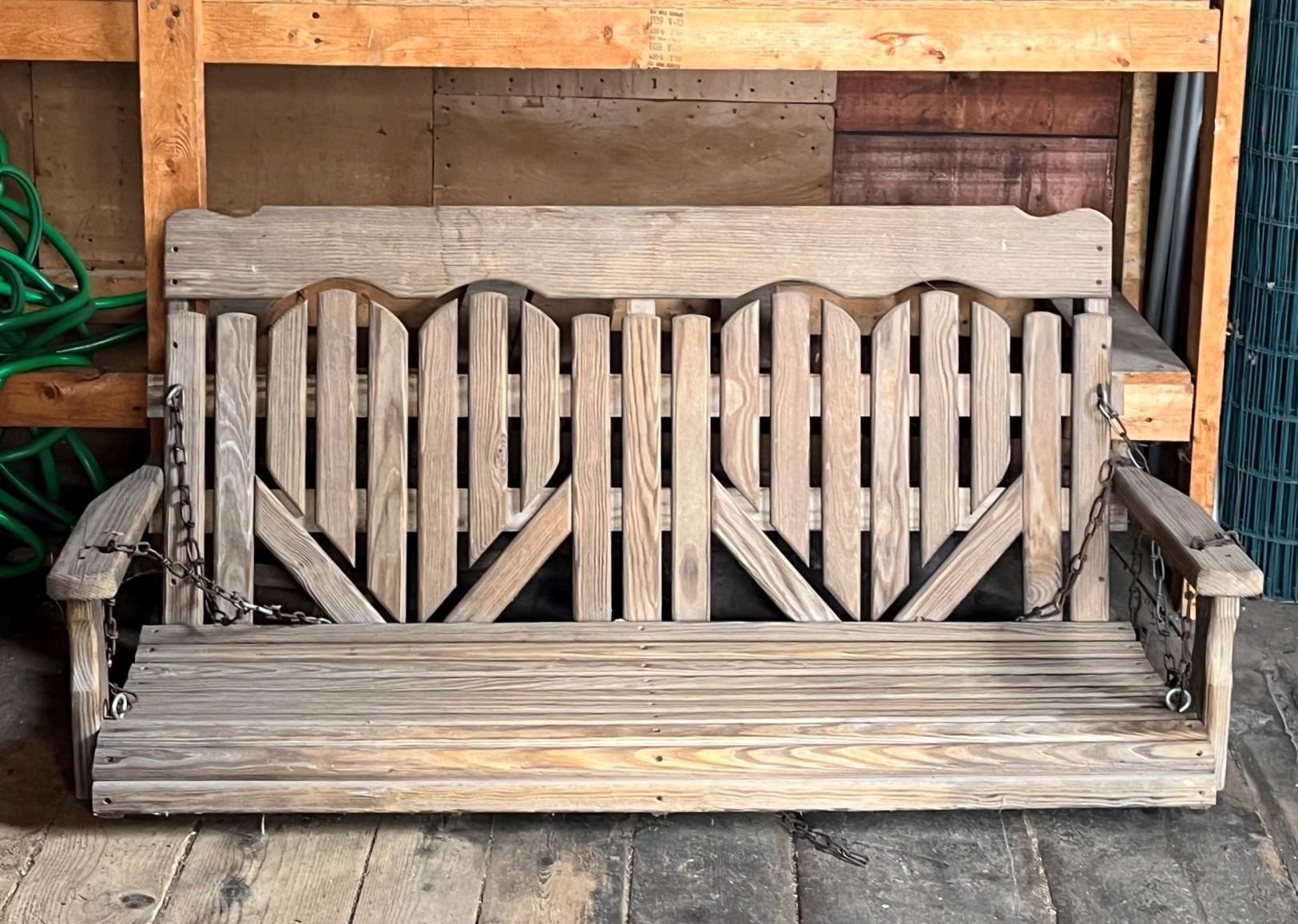 Weathered wooden porch swing with a slatted back and chain supports.