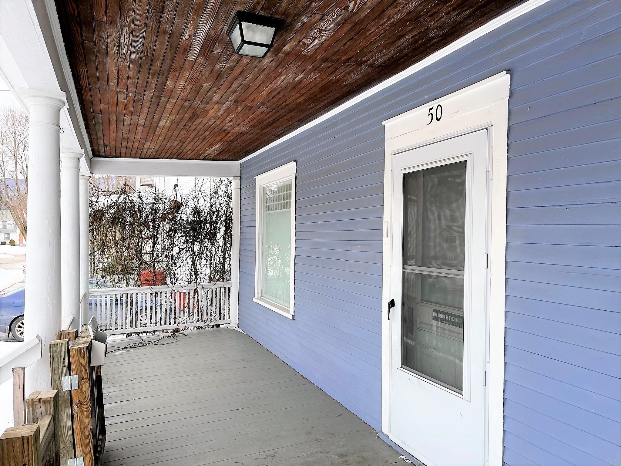 Covered porch with blue siding, white columns, and a screen door marked 50.