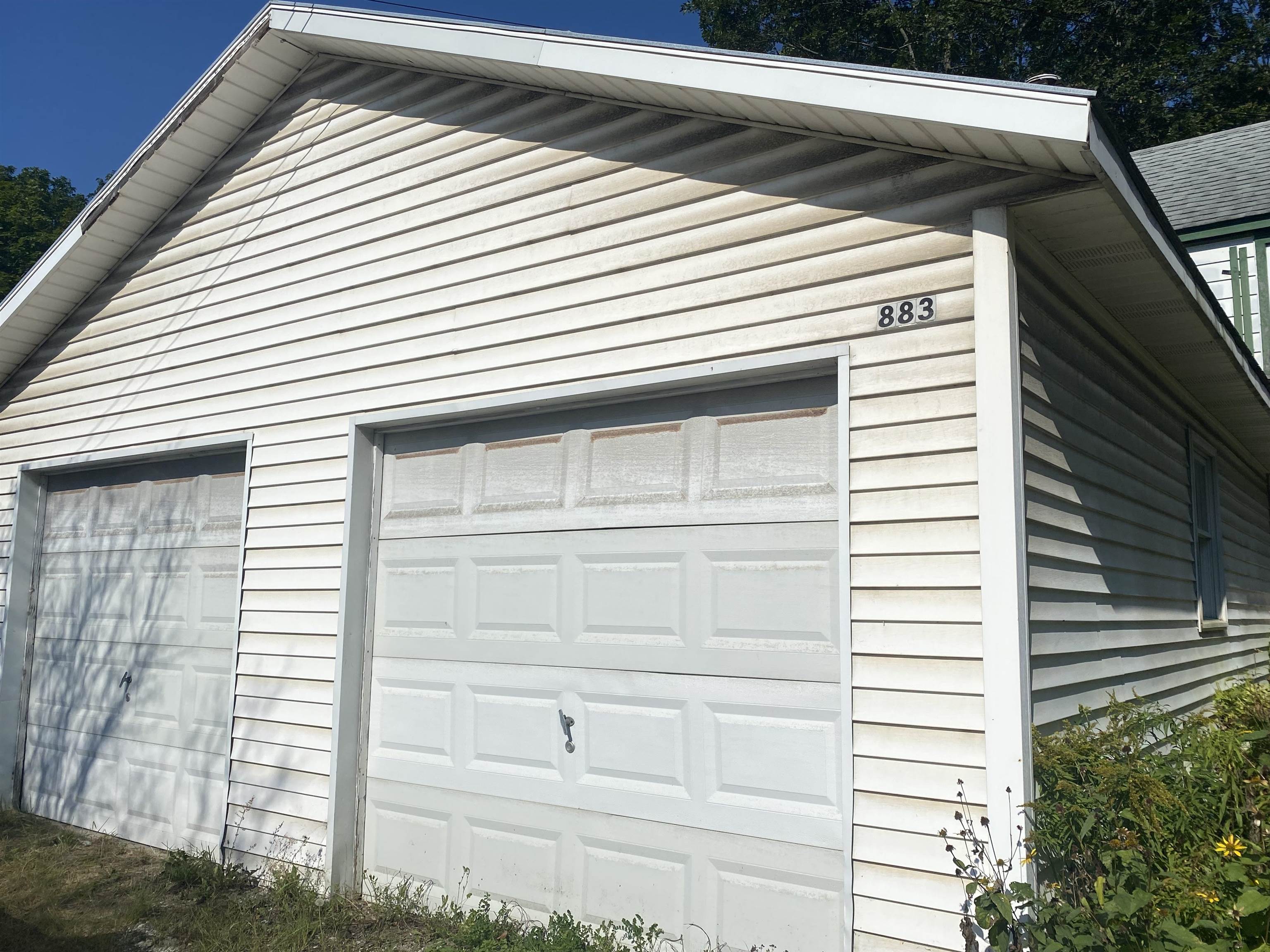 White two-bay garage with the number 883 above the larger door.