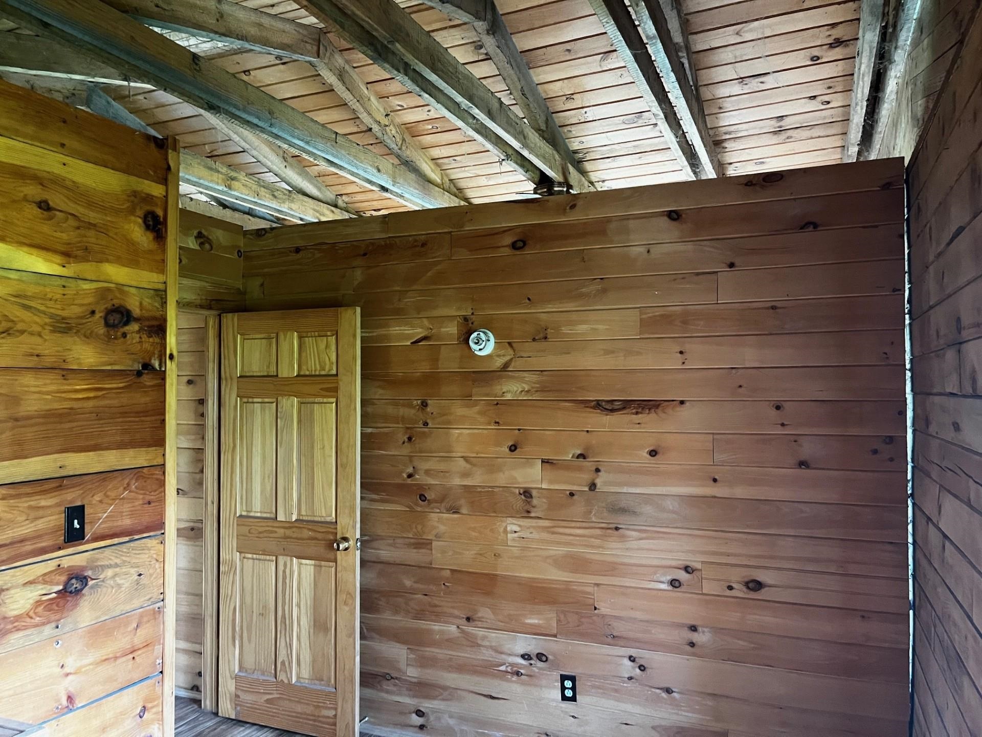 Wood-paneled room with exposed ceiling beams and a wooden door.