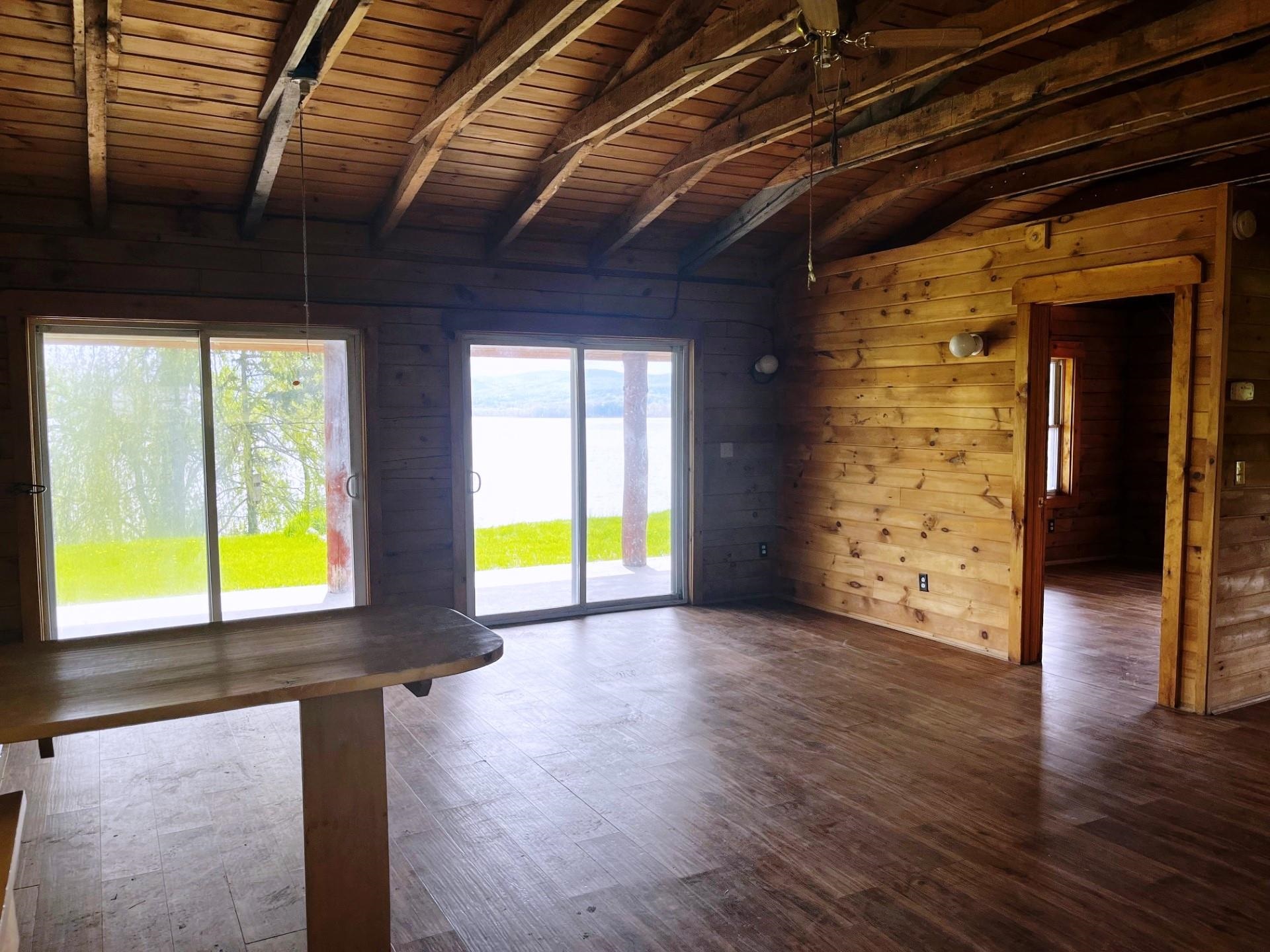 Wood-paneled room with exposed beams, sliding glass doors, and a lake view.