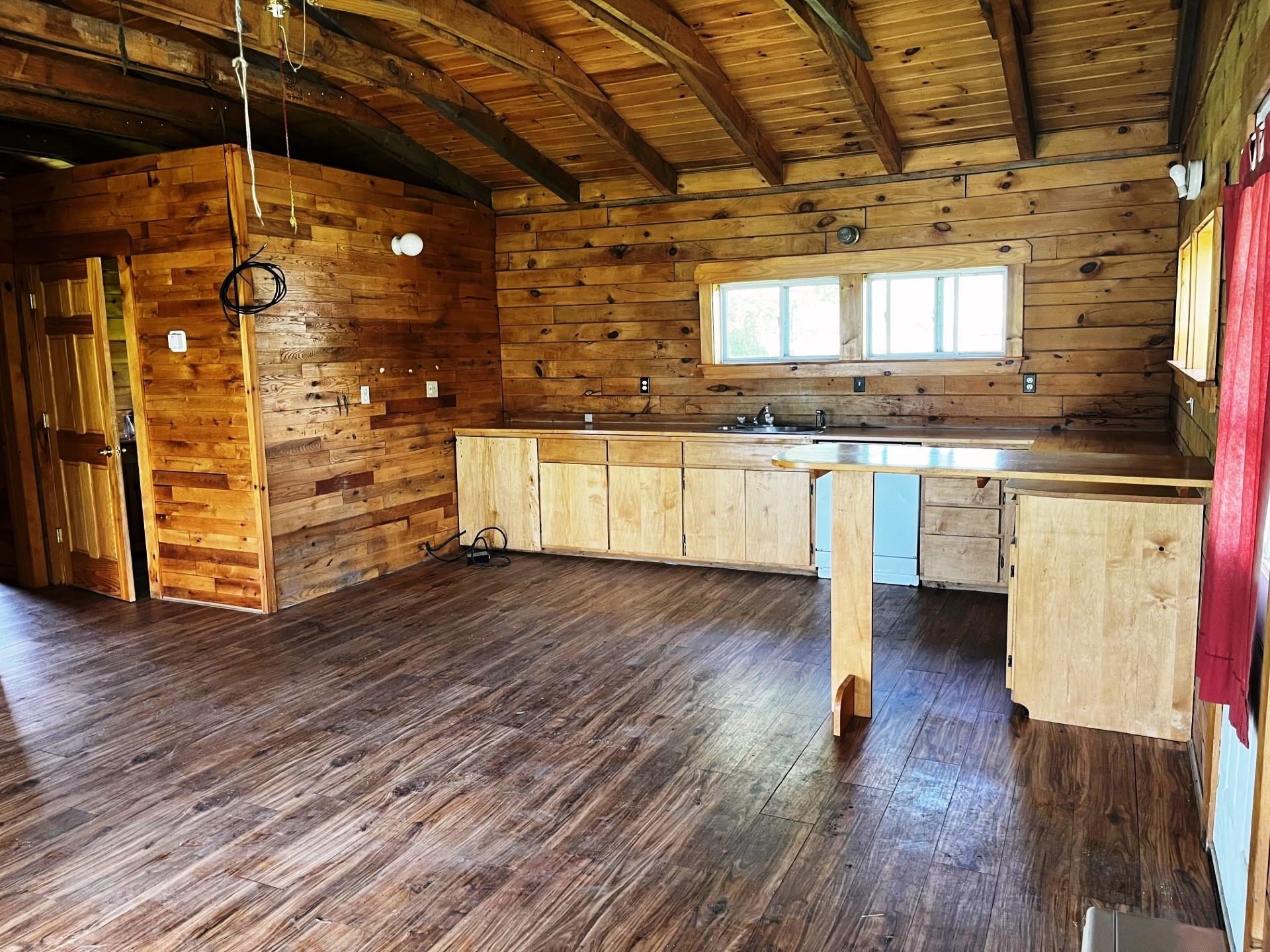 Rustic wood-paneled kitchen with exposed beams, light wood cabinets, and a peninsula counter.