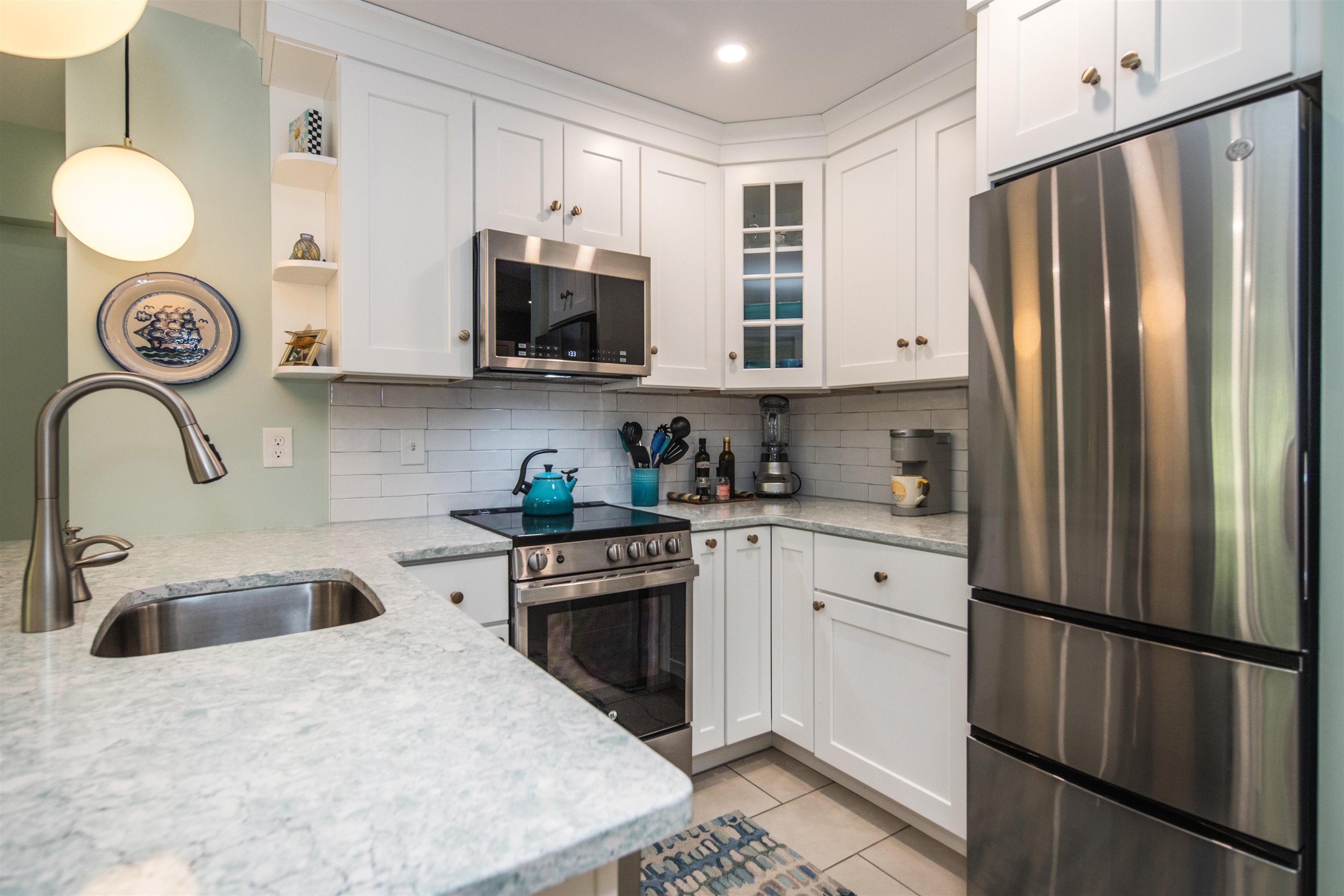 Kitchen with white cabinetry, stainless steel appliances, stone counters, and a subway tile backsplash.
