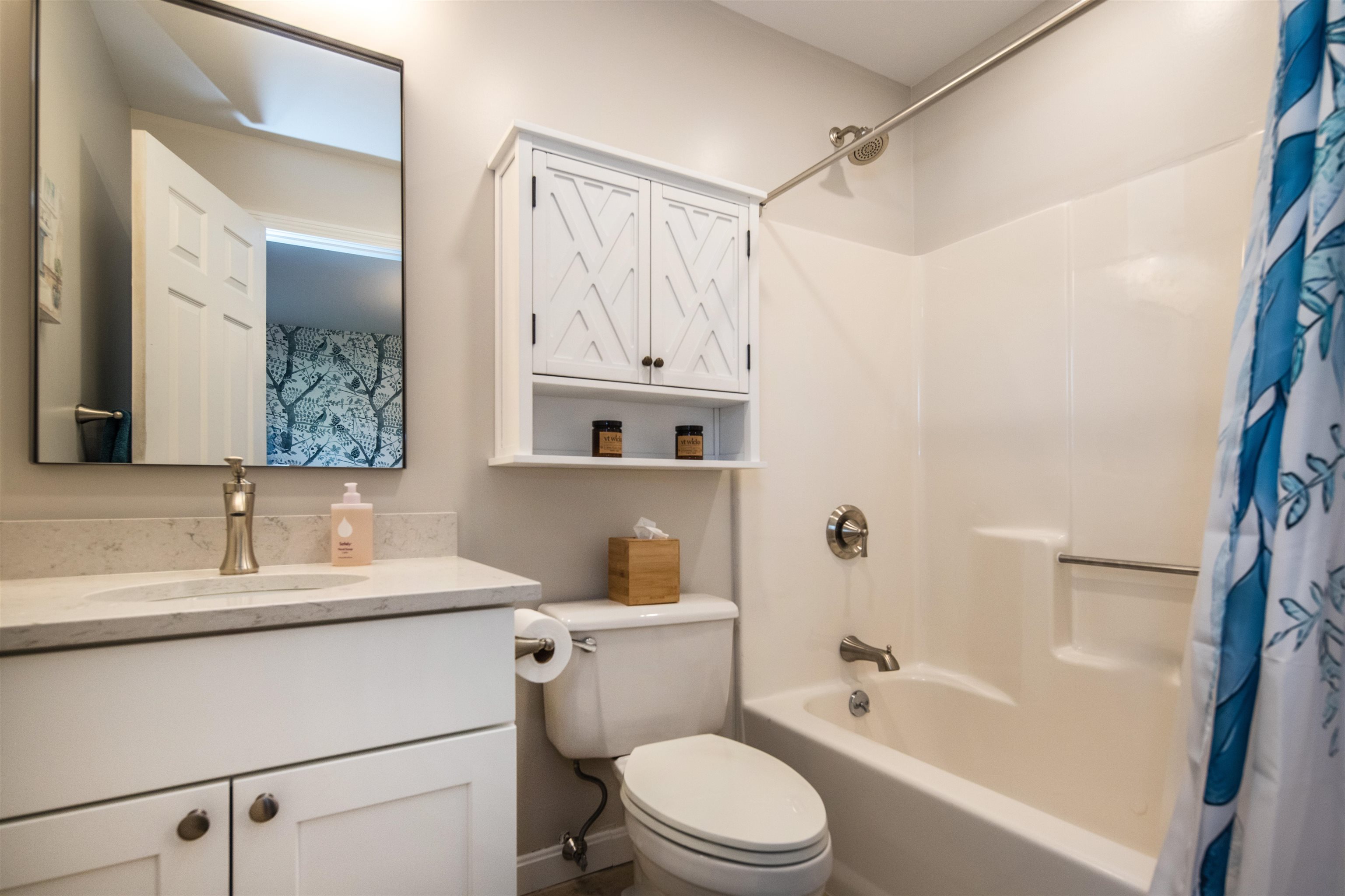 Bathroom with a white vanity, geometric cabinet doors, and a bathtub-shower combination.