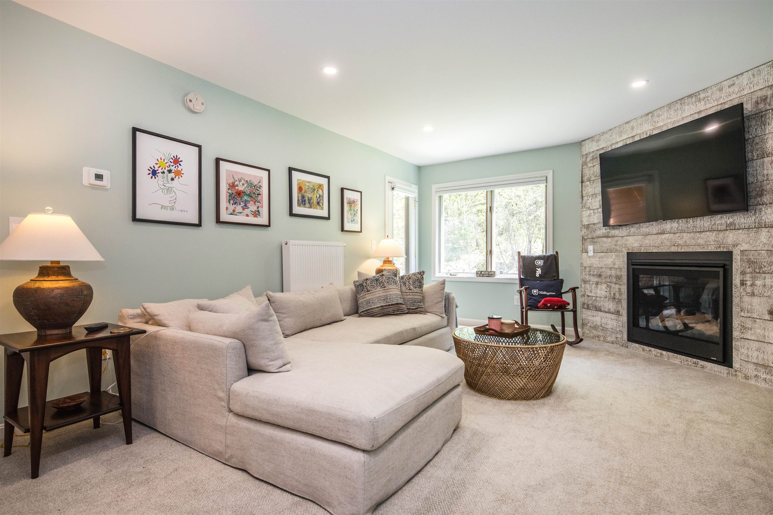 Living room with a pale sectional sofa, fireplace, and mounted television.