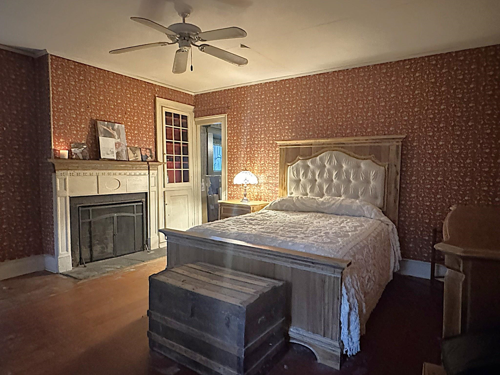 Bedroom with a four-poster bed and fireplace, featuring patterned red wallpaper.