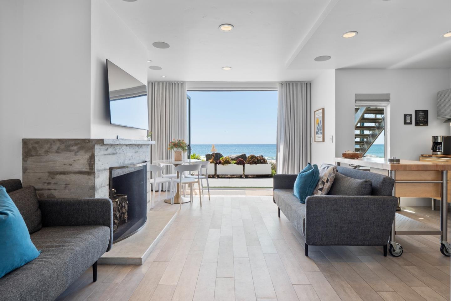 Furnished living room with a stone fireplace and ocean view through wide glass doors.