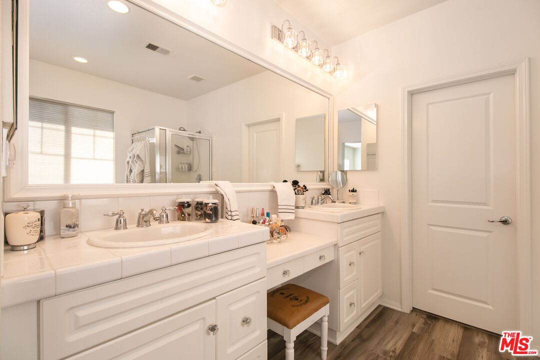 Bathroom with twin white vanities, a large mirror, and a glass-enclosed shower.