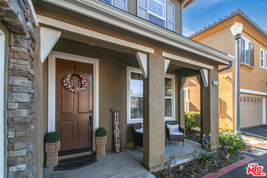 Covered home entry with a stone facade, wreath on the front door, and porch seating.