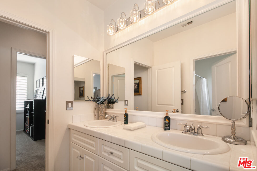 Bathroom with a long double-sink vanity, large mirror, and multi-light fixture.