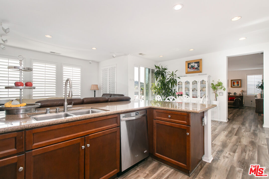 Open kitchen with dark wood cabinets, granite counters, and a large island with a double sink.