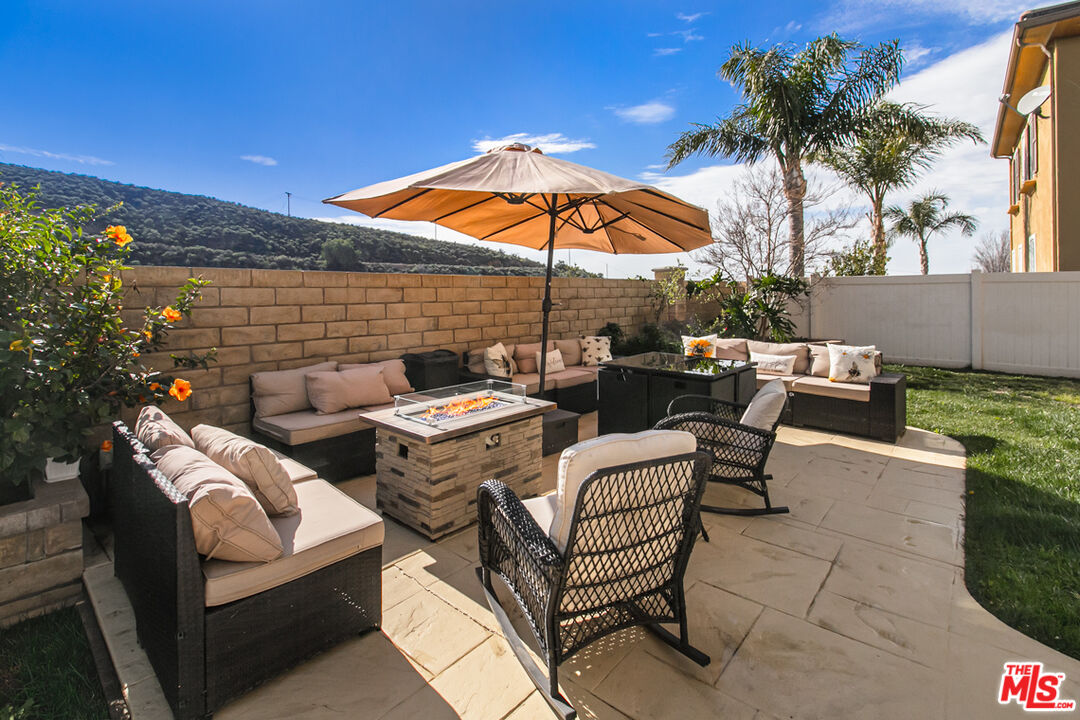 Furnished backyard patio with cushioned seating, a fire table, umbrella, and mountain views.